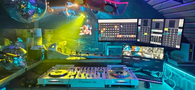 DJ-Pult mit Bildschirmen und buntem Licht in der Bar Zeitreise